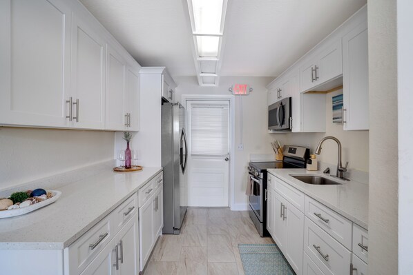 A modern kitchen with white cabinets, stainless steel appliances, and a blue rug.