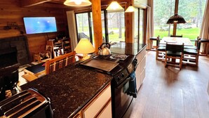 Une cuisine moderne dotée d’un grand îlot central, de poutres en bois, d’un téléviseur à écran plat et offrant une vue sur l’extérieur.