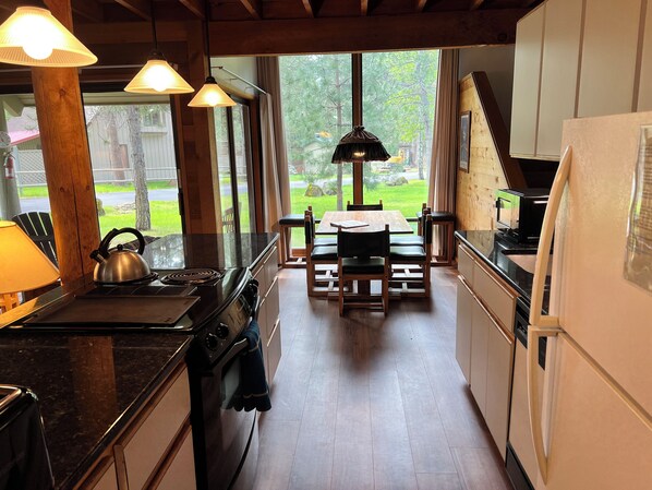 A kitchen with wooden cabinets, a stove, and a dining area with a table and chairs.