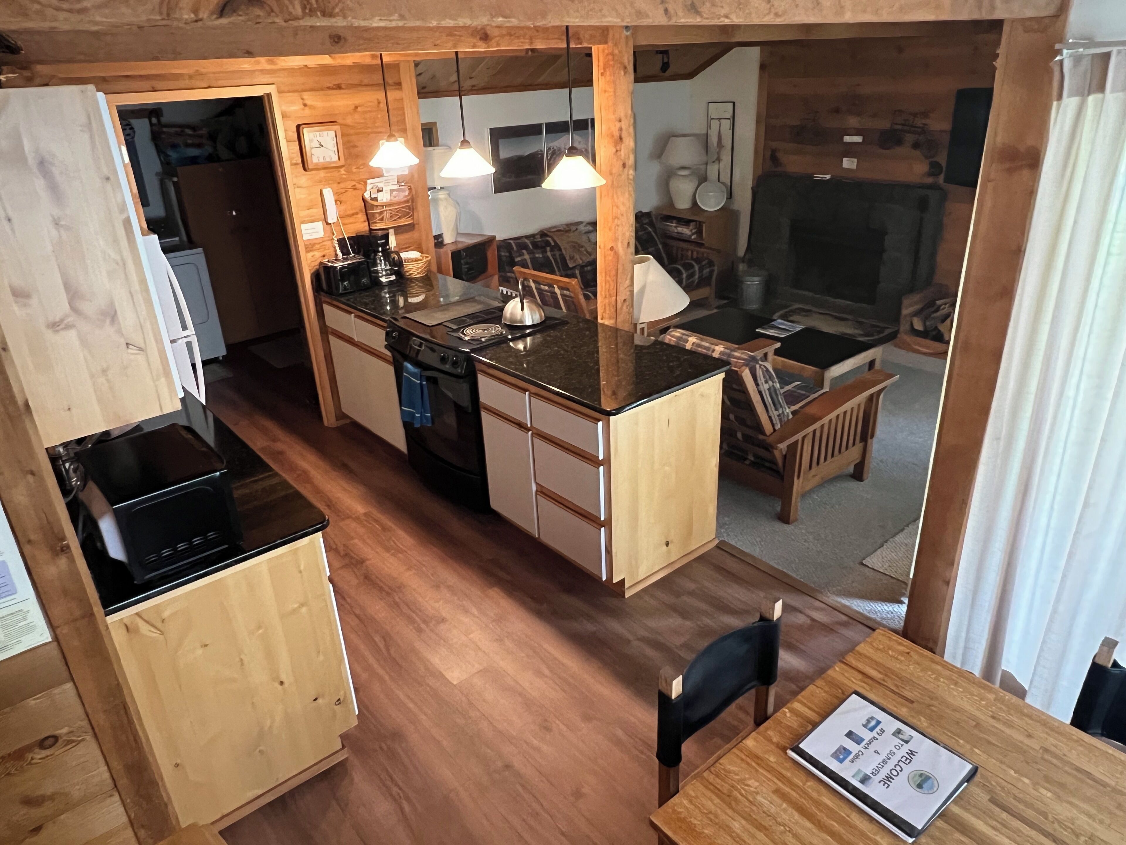 A compact kitchen with wooden cabinets, a black stove, and a dining area with a table and chairs.