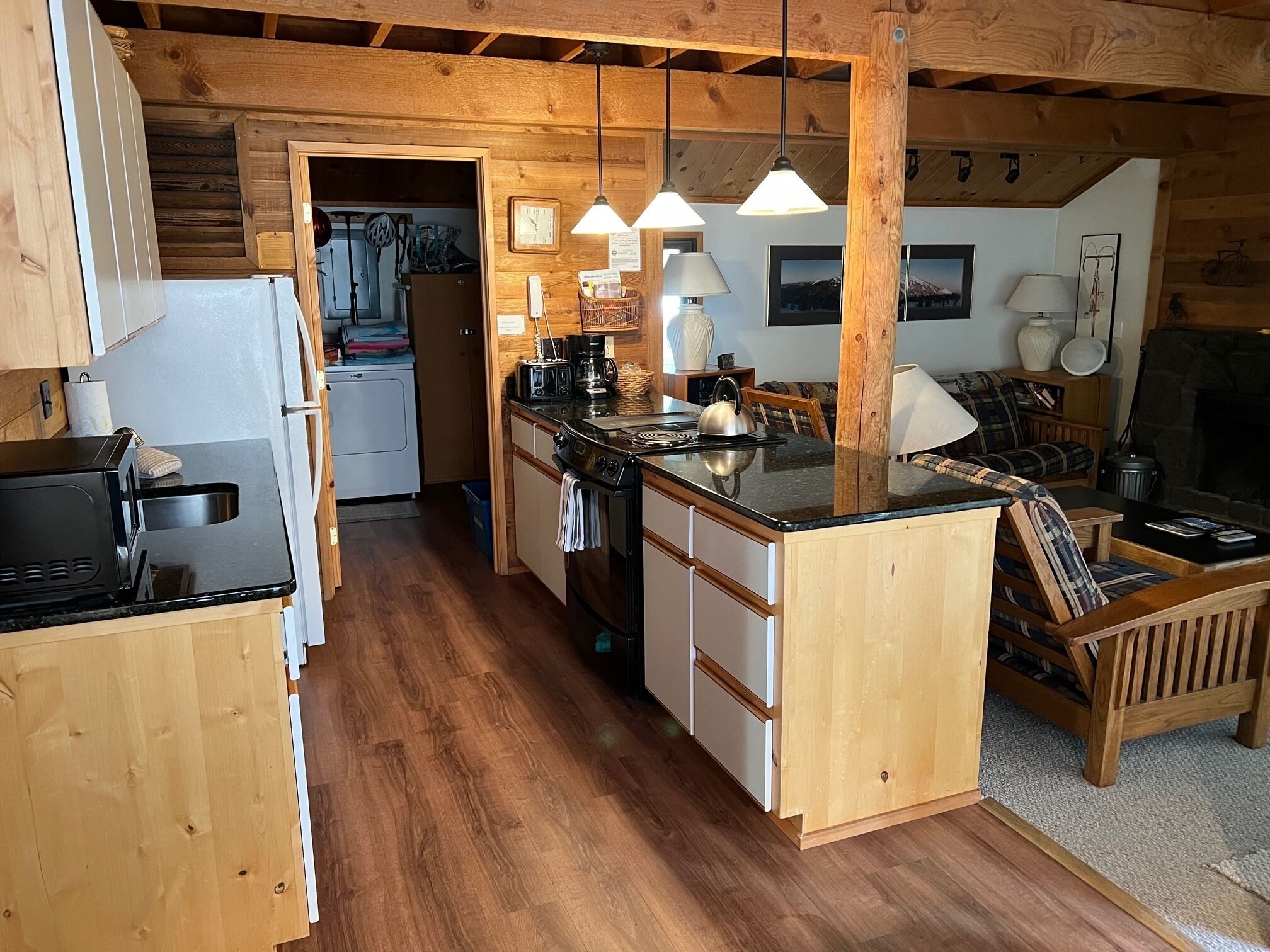 A compact kitchen with wooden cabinets, a central island, and hanging pendant lights.