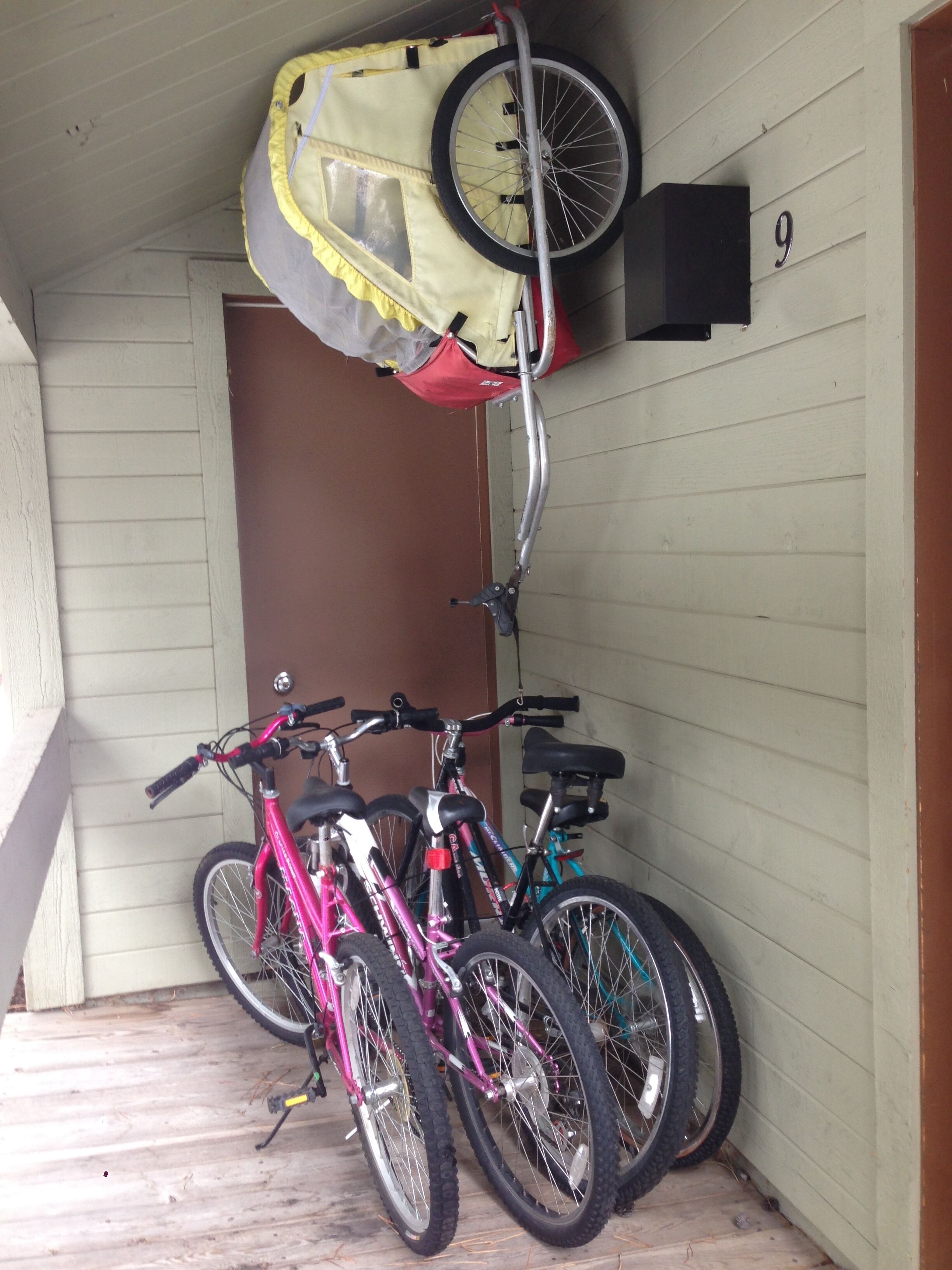 Varanda com três bicicletas, uma tenda amarela e uma porta com o número 9.