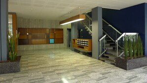 A spacious lobby with a marble floor, a staircase, and a reception area with a wooden counter. - Large charming apartment, bright, close to the center and the Old Town (Genève)