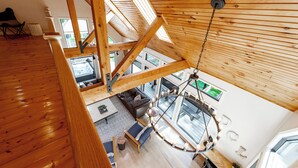 Een ruime loft met hoge plafonds, houten balken en dakramen.