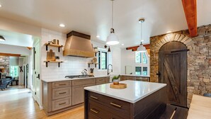 Een moderne keuken met een centraal eiland, houten kastjes en een wand met stenen accenten.