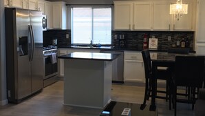 A modern kitchen with white cabinets, a stainless steel refrigerator, and a central island. - Elegant Las Vegas rental (Las Vegas)