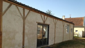 Un edificio con una puerta grande y ventanas, un muro de ladrillo y un tejado de tejas.