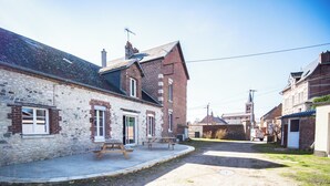 Una calle estrecha con casas tradicionales de ladrillo, un edificio de piedra y una mesa de picnic al frente.
