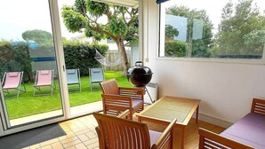 Un patio con mesa y sillas, una parrilla y vistas al jardín.