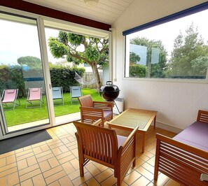 Un patio con mesa y sillas, una parrilla y vistas al jardín.