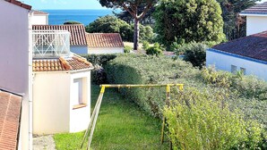 Una zona residencial con vistas al mar, un jardín bien cuidado y un edificio blanco con techo de tejas.