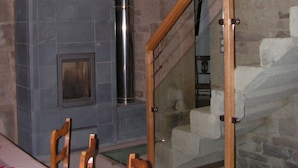 A room with a stone wall, a fireplace, a wooden staircase, and a dining table with chairs. - DETACHED HOUSE for 11 people, accessible to people with limited mobility. (Xertigny)