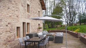 An outdoor patio with a stone building, a table with chairs, and a large umbrella. - DETACHED HOUSE for 11 people, accessible to people with limited mobility. (Xertigny)