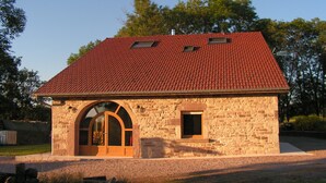 A stone building with a red-tiled roof, a large arched doorway, and a small window. - DETACHED HOUSE for 11 people, accessible to people with limited mobility. (Xertigny)
