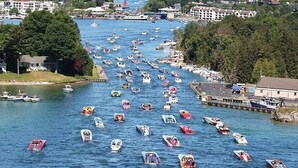 A river with numerous boats and a dock on the right. - Cozy Boat House Lake Charlevoix: Amazing View/Pool (Charlevoix)