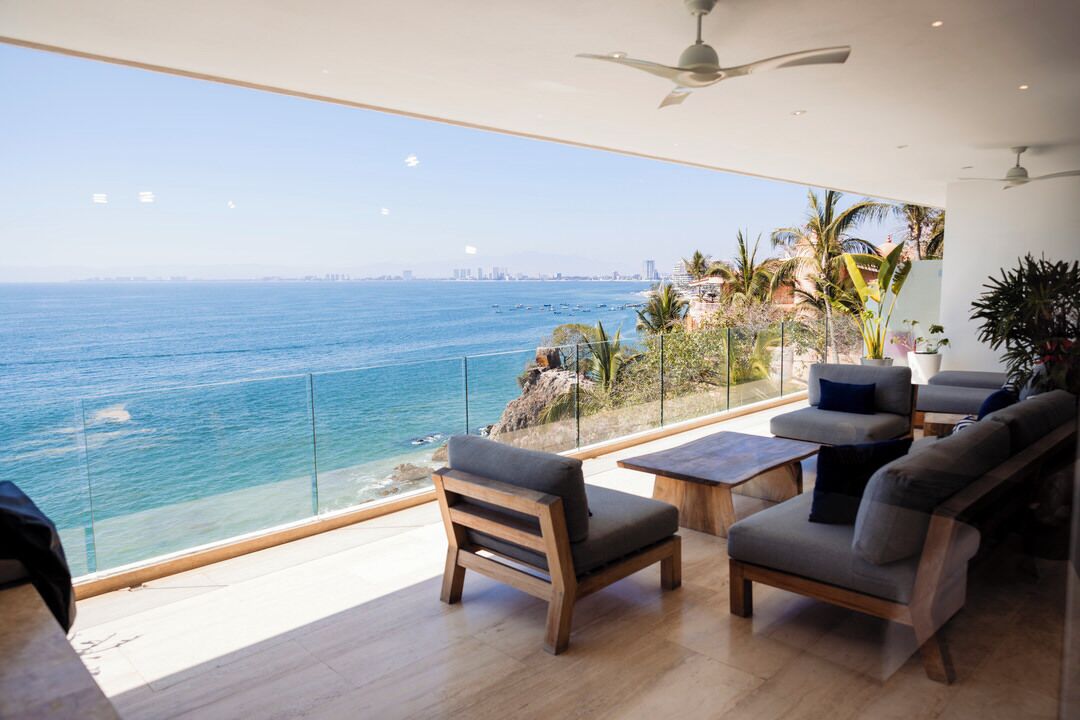 Un salon moderne avec vue sur l’océan, comprenant un canapé, des fauteuils et une table basse.