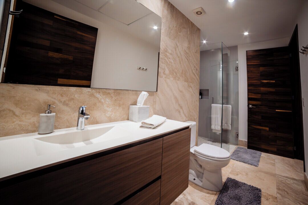Une salle de bain moderne avec un grand miroir, un lavabo, des toilettes et un espace douche.