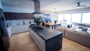 Una cocina moderna con una isla central, electrodomésticos integrados y una zona de comedor con sofá y mesa.