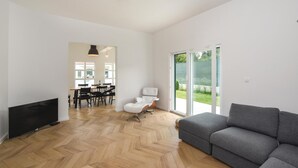 A spacious living area with a grey sofa, a TV, a dining table with chairs, and a white armchair. - Luxurious home in Hrvace (Hrvace)