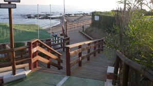 Een houten looppad dat naar een strand leidt, met een bord waarop staat dat voetgangers voorrang hebben.