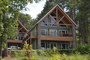 A two-story lodge with a balcony and a covered deck, surrounded by trees. - Bellawood Resort #1 Lakefront Cabin with Boat Slip - Unobstructed View! (Greers Ferry)