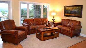 A living room with a brown leather sofa set, a wooden coffee table, and a painting on the wall. - Bellawood Resort #1 Lakefront Cabin with Boat Slip - Unobstructed View! (Greers Ferry)