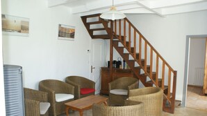 Un salon avec des meubles en osier, une table en bois et un escalier.