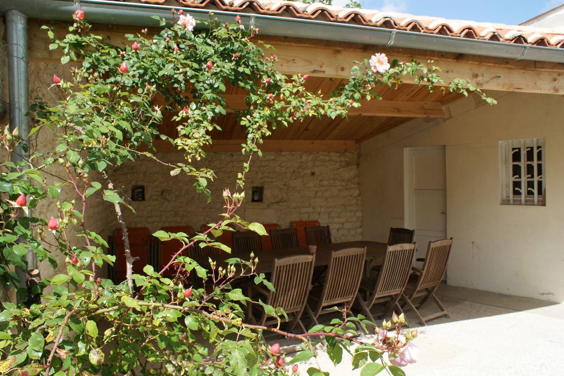 A covered outdoor seating area with stone walls and wooden furniture.