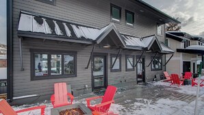 A house with a covered porch and a fire pit area with red Adirondack chairs. - Woodside Ave - Close to Sundance Locations - Private Hot Tub (Park City)
