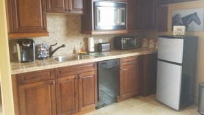 A kitchen with wooden cabinets, a microwave, a toaster, a coffee maker, and a refrigerator. - Vacation Rental Available (Scottsdale)