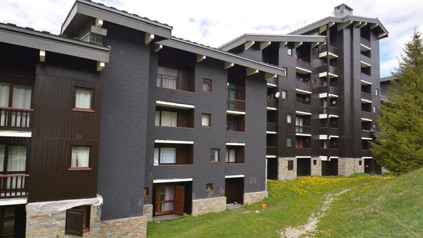 A multi-story hotel with a modern design, featuring balconies and a stone facade. - Cozy 4-Person Apartment, Ski-In/Ski-Out, West-Facing Balcony, Les Menuires (Les Menuires)