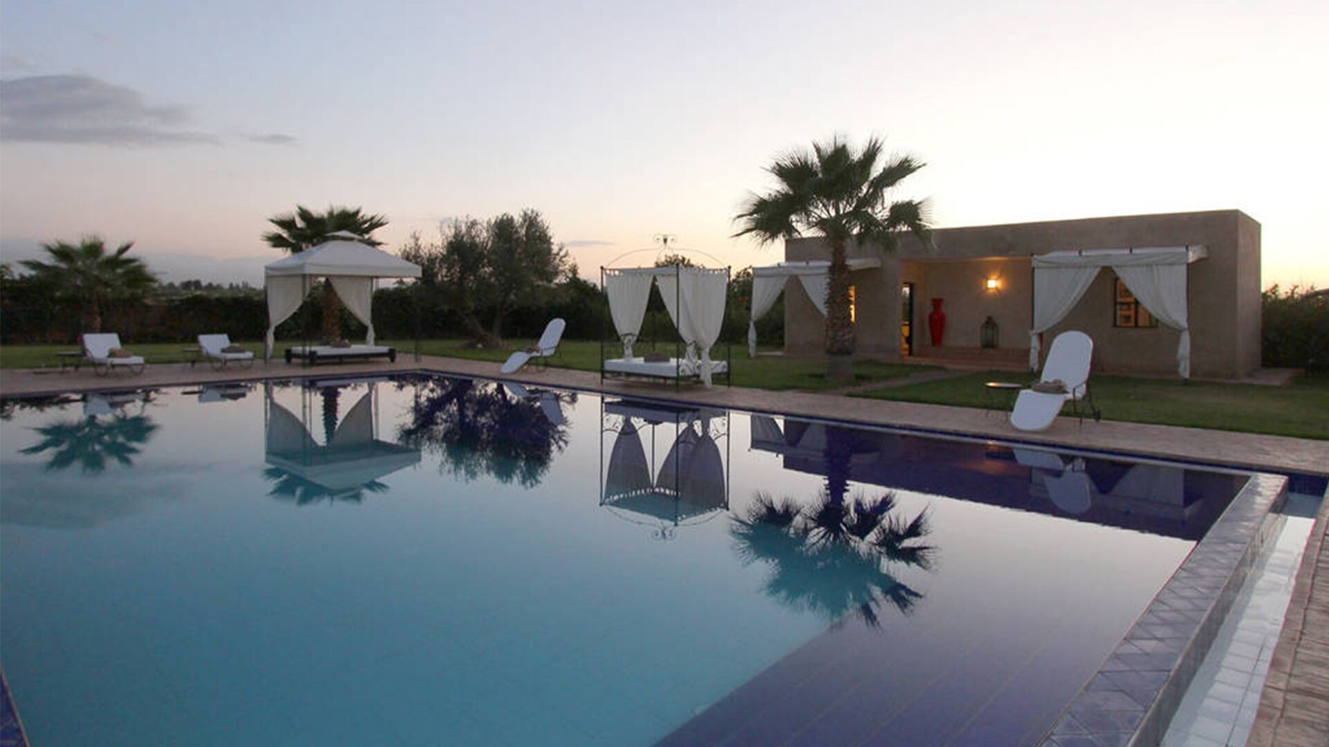 A swimming pool with lounge chairs and a covered seating area.