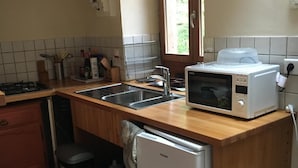 A compact kitchen with a sink, a microwave, a refrigerator, and wooden countertops. - Small house in the middle of the forest.  (Saint-Remy)