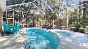 Une piscine extérieure couverte, dotée d’un parasol, et entourée de chaises et d’une petite table.