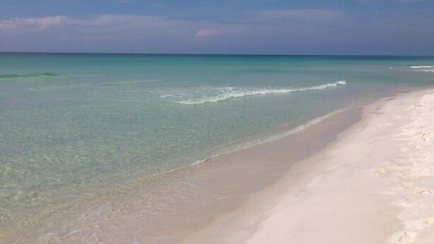 Une plage à l’eau turquoise et limpide, bordée d’un rivage sablonneux.