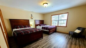 A bedroom with two wooden beds, a window, and a chair. - Beautiful Lakefront w Private Beach/Hot Tub/ Boats/ Fire Pit (Long Pond)
