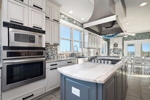 A modern kitchen with stainless steel appliances, a large island, and a view of the city.