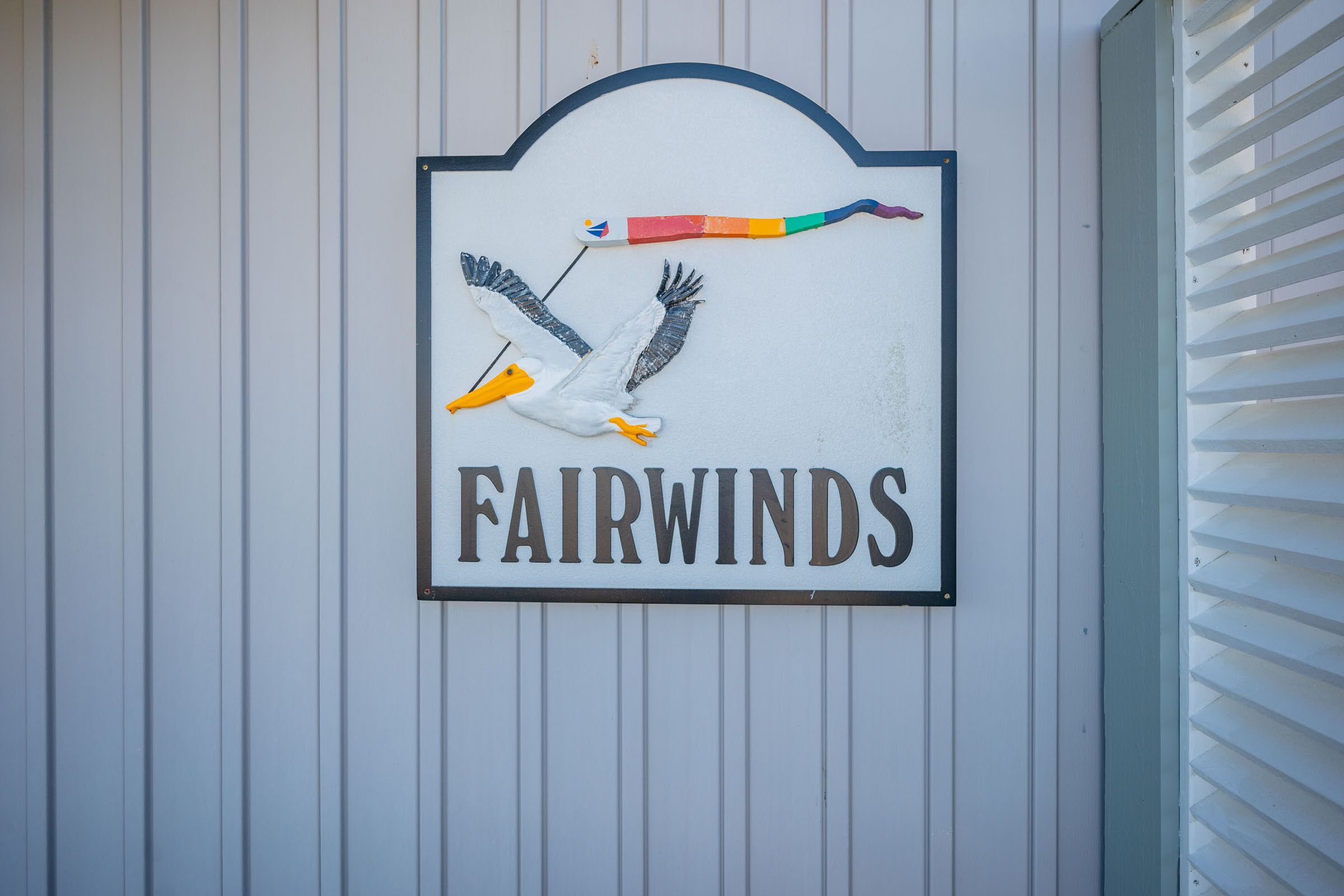 A sign with a swan and the word "FAIRWIND" on a white wall.