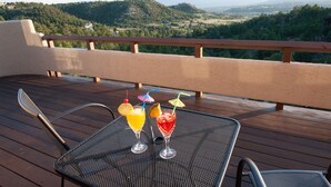 A deck with a table set for drinks, overlooking a mountainous landscape. - Hidden Gem: Heated Pool, Gorgeous Mountain Views, 2.4 Acres inside City, A/C, EV (Colorado Springs)