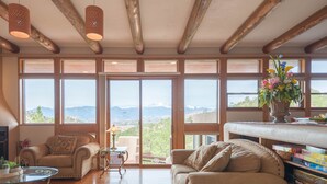 A spacious living room with large windows, a fireplace, and a view of mountains. - Hidden Gem: Heated Pool, Gorgeous Mountain Views, 2.4 Acres inside City, A/C, EV (Colorado Springs)