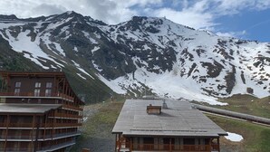 Uma pousada de montanha com fachada de madeira e vista para picos nevados.
