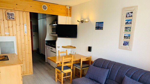 Um espaço compacto com cozinha compacta, área de refeições e sofá.