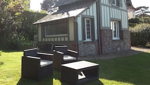 Ein Haus im Tudor-Stil mit einem großen Fenster und einer Terrasse mit Gartenmöbeln.