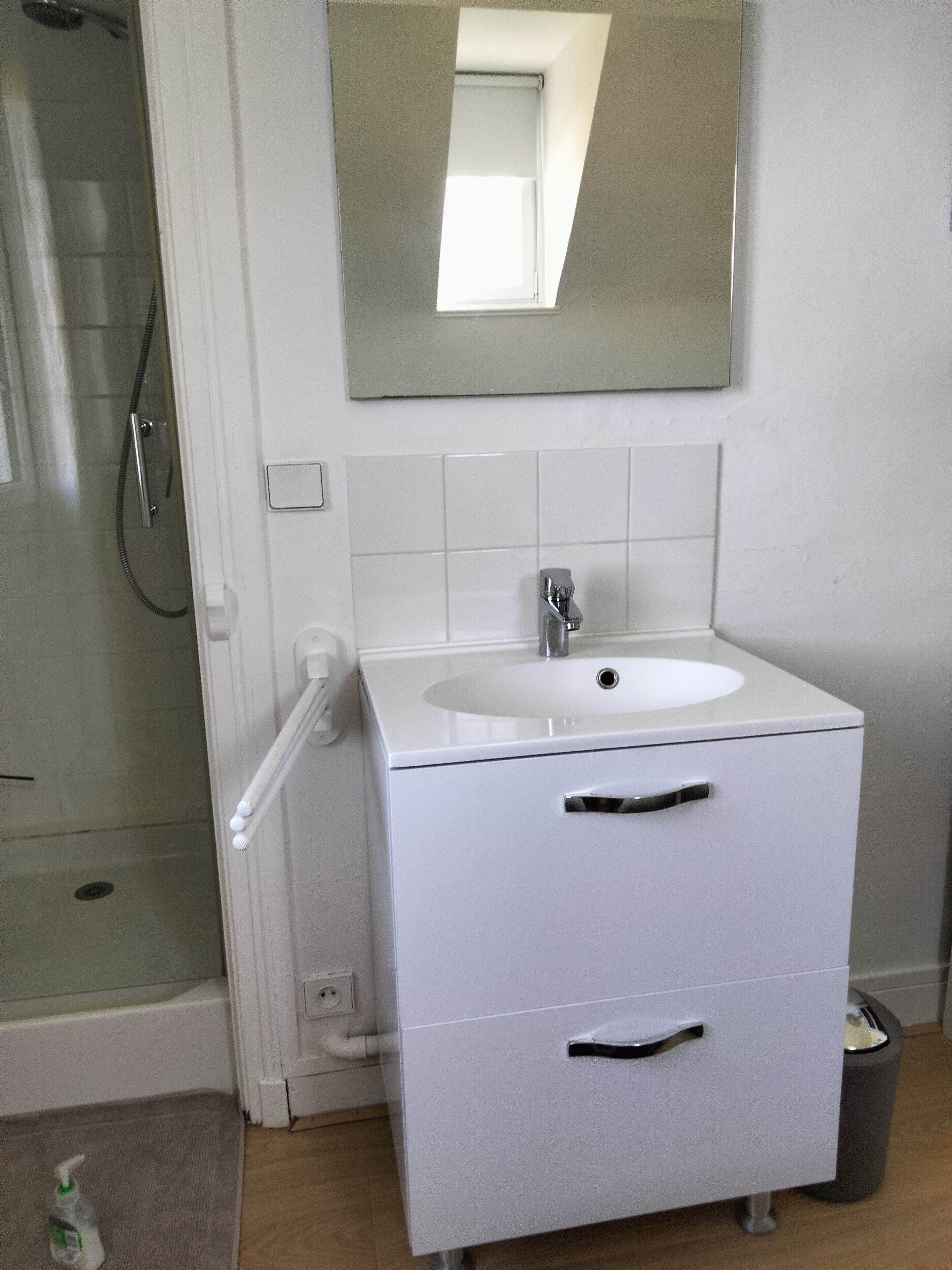 A bathroom with a white sink, mirror, and a shower.