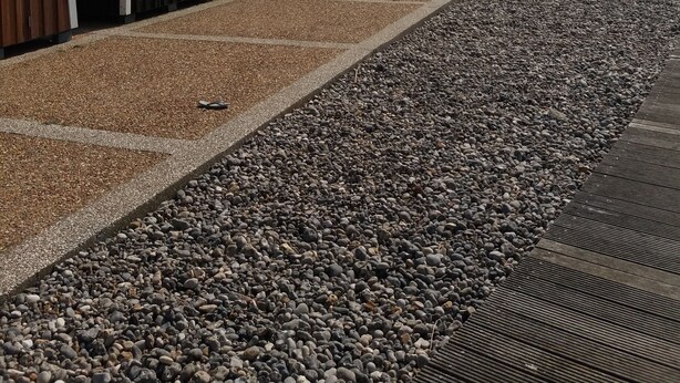 Eine Reihe von Strandkörben mit einem Kiesweg, der zu ihnen führt.