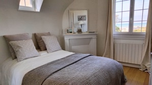 Ein Schlafzimmer mit Bett, Kissen, einem Nachttisch mit Lampe und einem Fenster mit Blick.