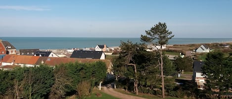 A coastal residential area with houses, a clear sky, and a view of the sea.