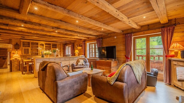 A cozy log cabin interior with a living room, dining area, and kitchen.