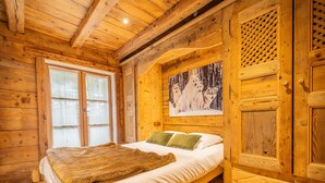 A wooden cabin room with a bed, a window, and a door.