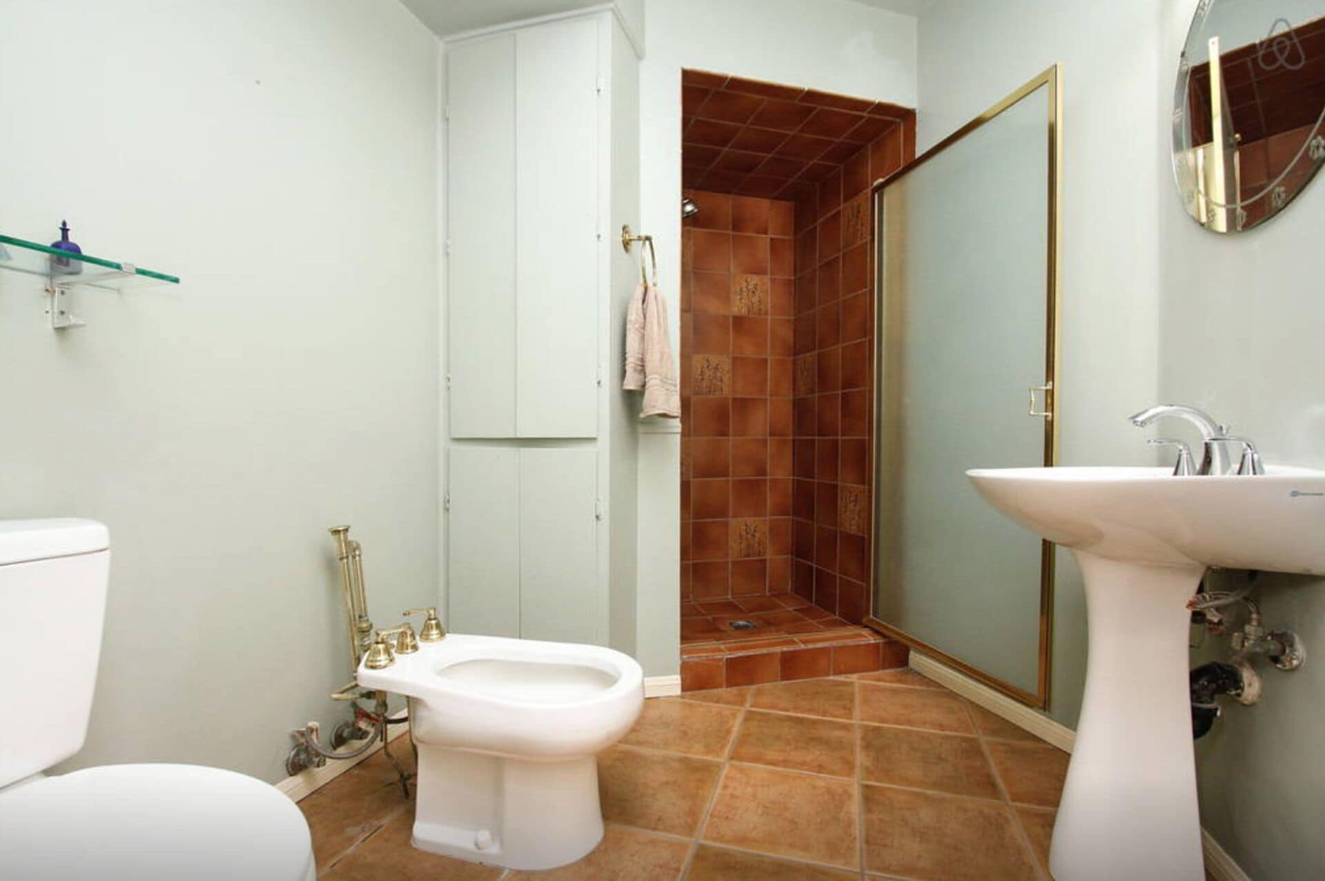 Ein Badezimmer mit Toilette, Bidet, Waschbecken und Duschbereich.